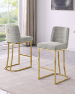 Two modern counterheight chairs with textured light gray bouclé upholstery and gold metal frames, shown in a bright living room setting.