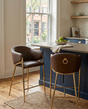 Counterheight bar stools in brown faux leather with gold chrome legs and ring handle