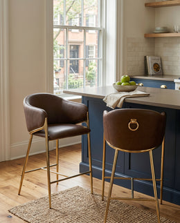 Counterheight bar stools in brown faux leather with gold chrome legs and ring handle