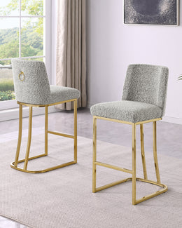 Two modern counterheight chairs with textured light gray bouclé upholstery and gold metal frames, shown in a bright living room setting.