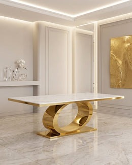 A luxury dining table featuring a polished white marble top and a sculptural, curved gold metal base, set in a high-end modern interior.